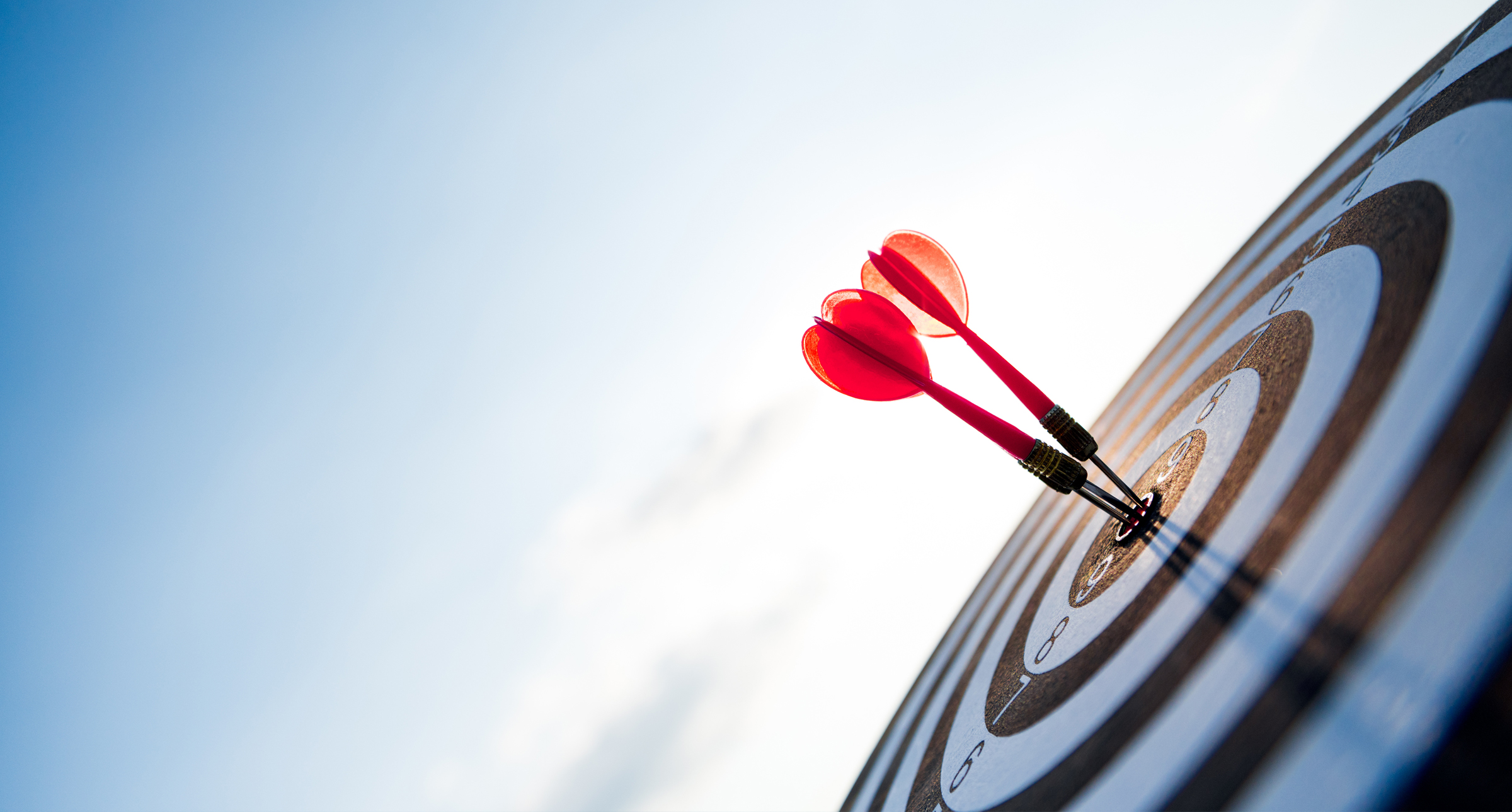 Photograph of a dart board with three arrows in the bullseye.